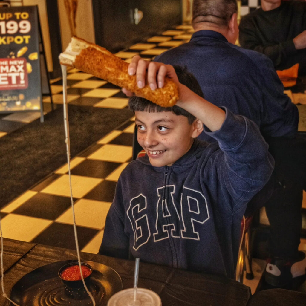 Kid doing an epic cheesepull with El Masivo Gringo at Frato's Schaumburg