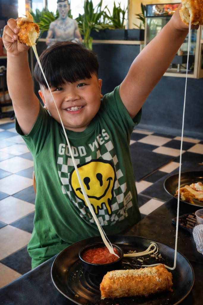 Kid enjoying Frato's pizza with a delicious cheese pull