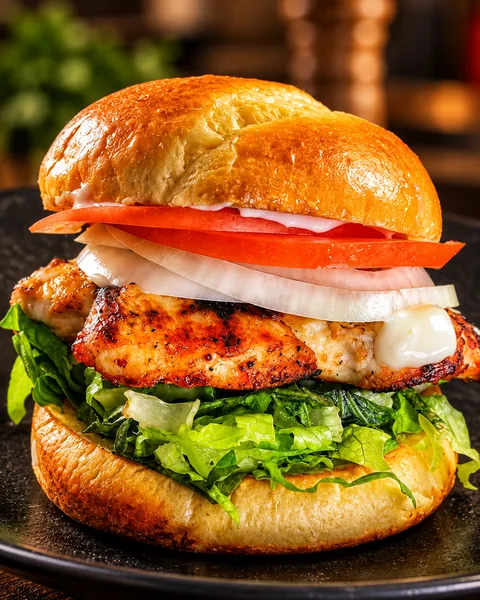 Grilled halal chicken sandwich with lettuce, tomato and onion on a toasted bun at Frato’s