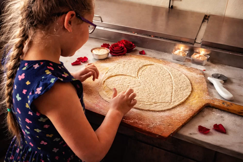 Young girl shaping heart-shaped pizza dough by hand at Frato’s Culinary Kitchen in Schaumburg, IL