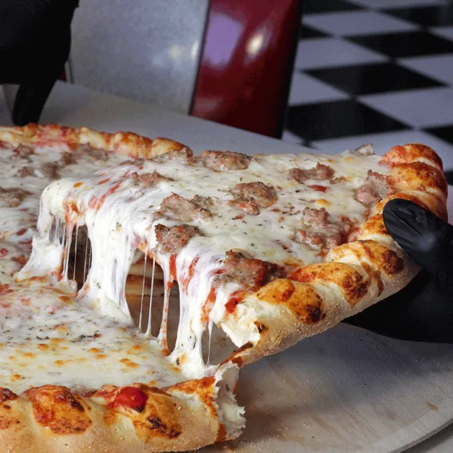 Cheese pull on a slice of Frato’s sausage pizza